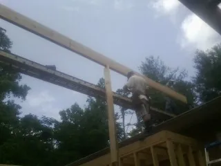 Carpenter setting a ridge beam over a new addition frame — Ice Dam Removal by Roofing Brothers in Lolita