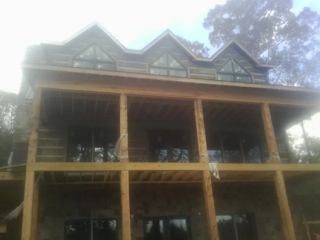 Dormers and porch framing on a large log home under construction — Roof Coating work by our crew in Lolita