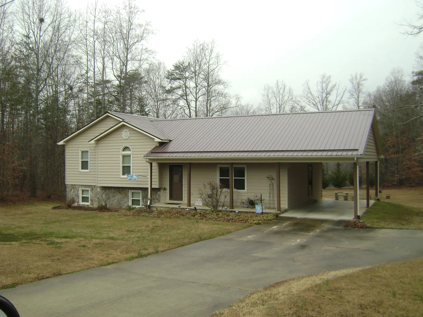 Brown metal roof on a tan split level home with an attached carport in Lolita