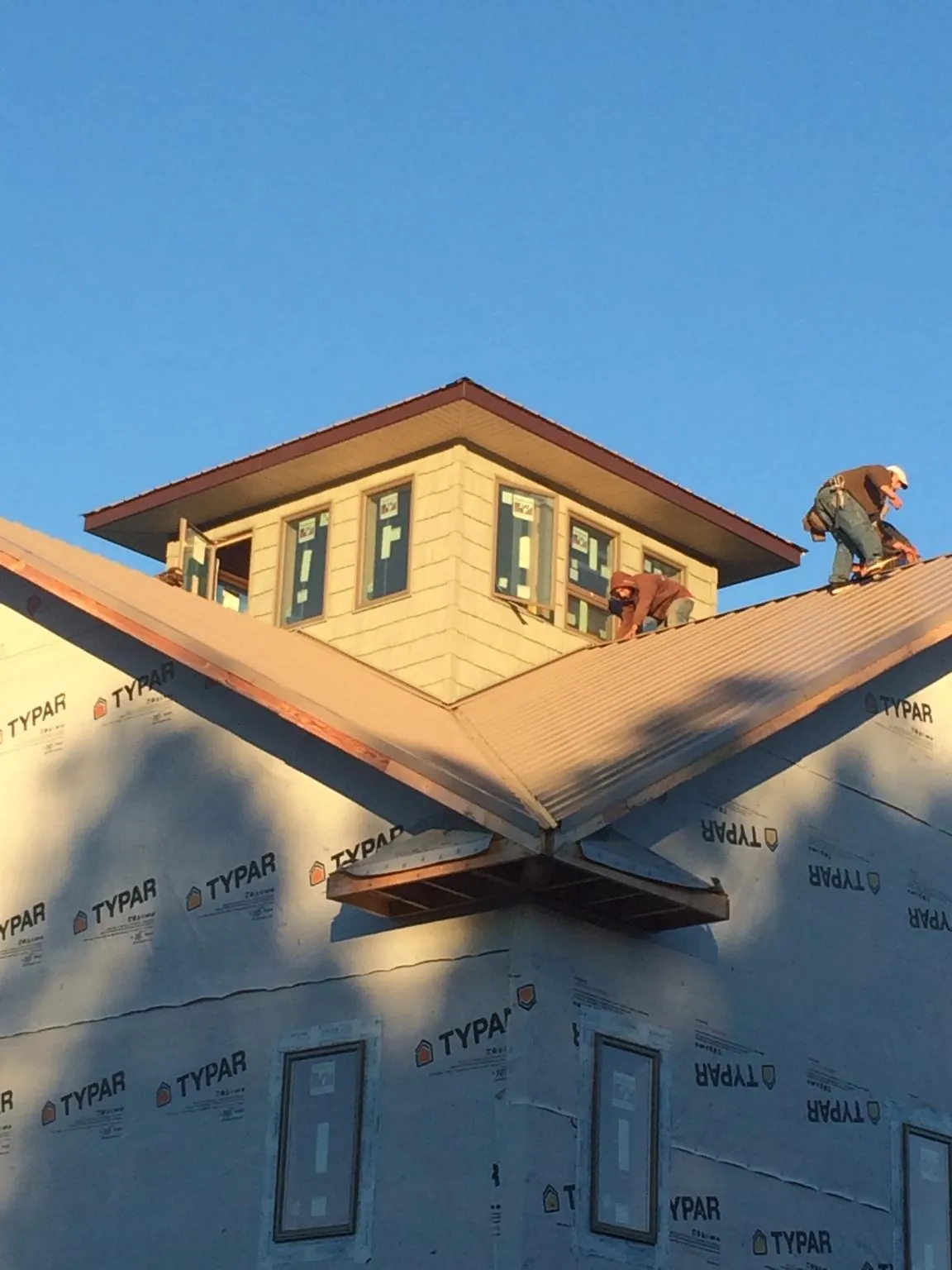 Roofers working around a rooftop cupola on a new metal roof at sunset — Roof Waterproofing in Lolita by Roofing Brothers